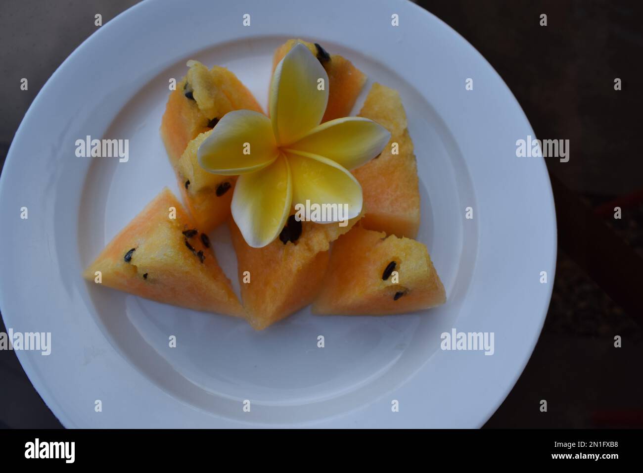Gelbe Wassermelonenstücke auf einem weißen Teller Stockfoto