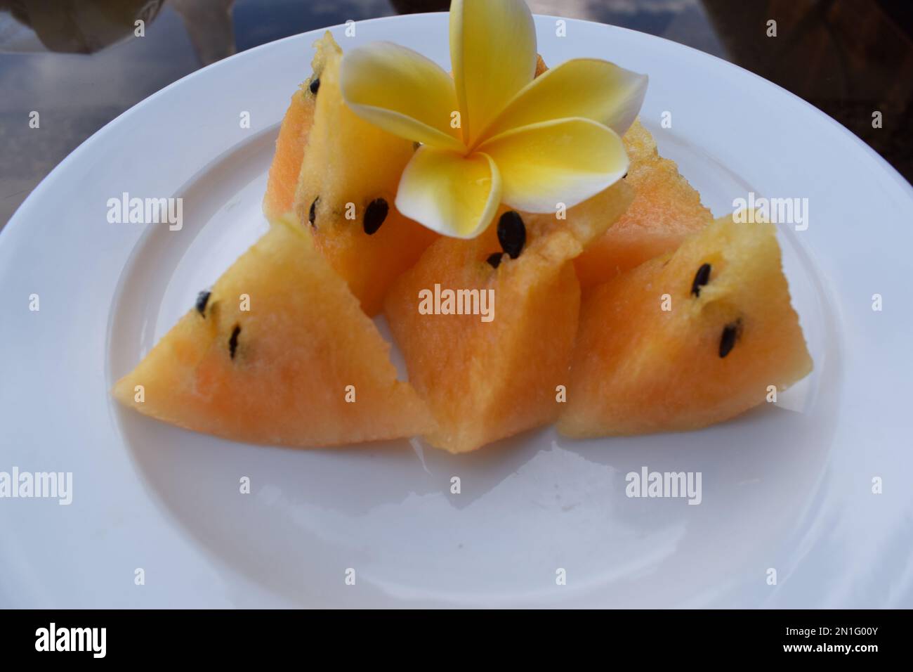 Gelbe Wassermelonenstücke auf einem weißen Teller Stockfoto