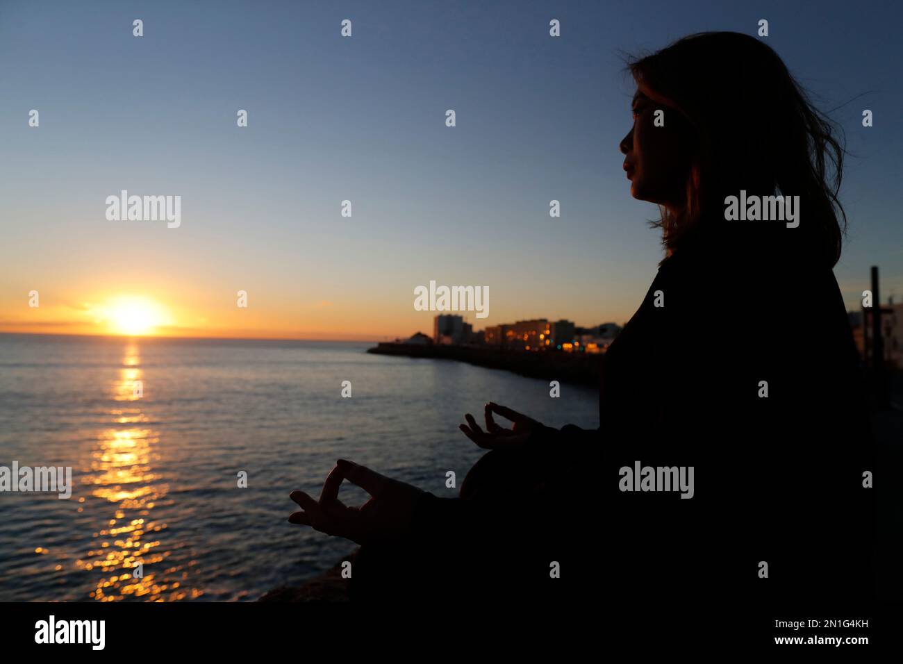 Frau, die Yoga-Meditation am Meer bei Sonnenuntergang als Konzept für Stille und Entspannung praktiziert, Cadiz, Andalusien, Spanien, Europa Stockfoto