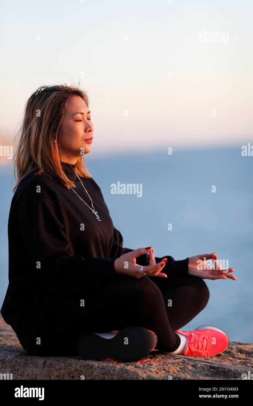 Frau, die vor Sonnenuntergang Yoga-Meditation am Meer praktiziert, als Konzept für Stille, Harmonie und Entspannung, Spanien, Europa Stockfoto