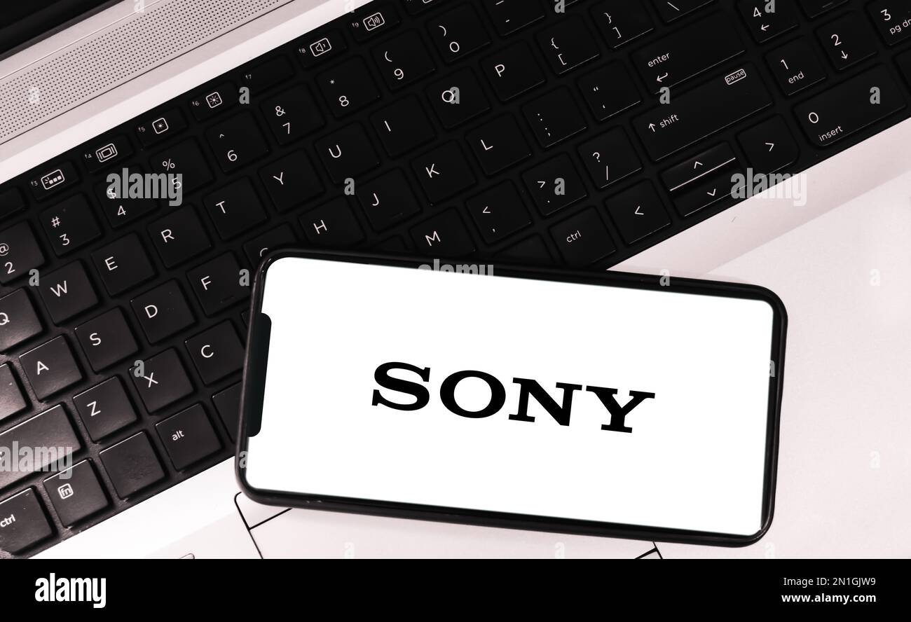 Sony auf Mobilgerät mit Laptop im Hintergrund, Editorial Stockfoto