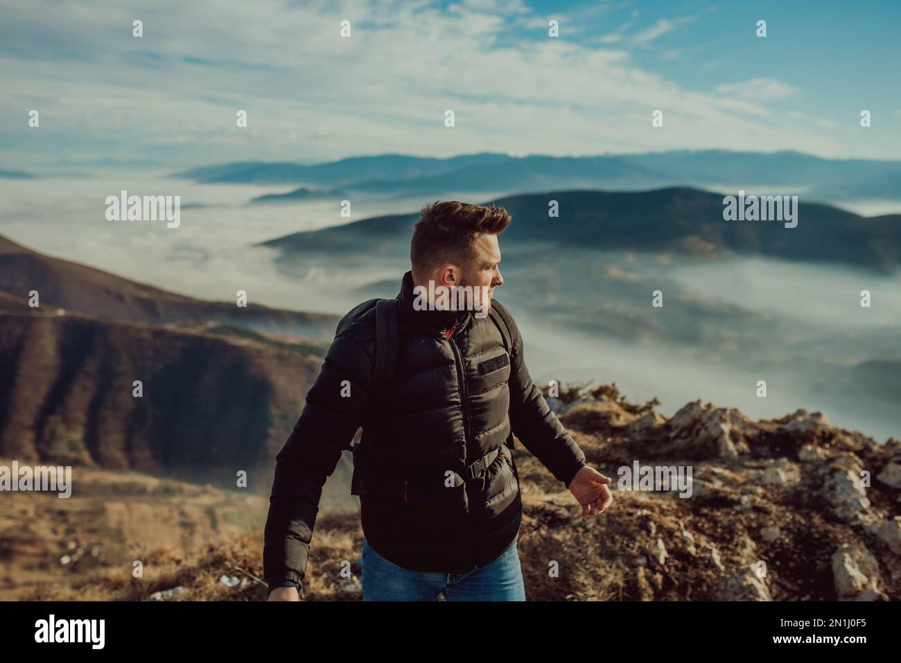 Ein Bergsteiger in einer Jacke und mit einem Rucksack, der oben auf dem  Berg steht Stockfotografie - Alamy