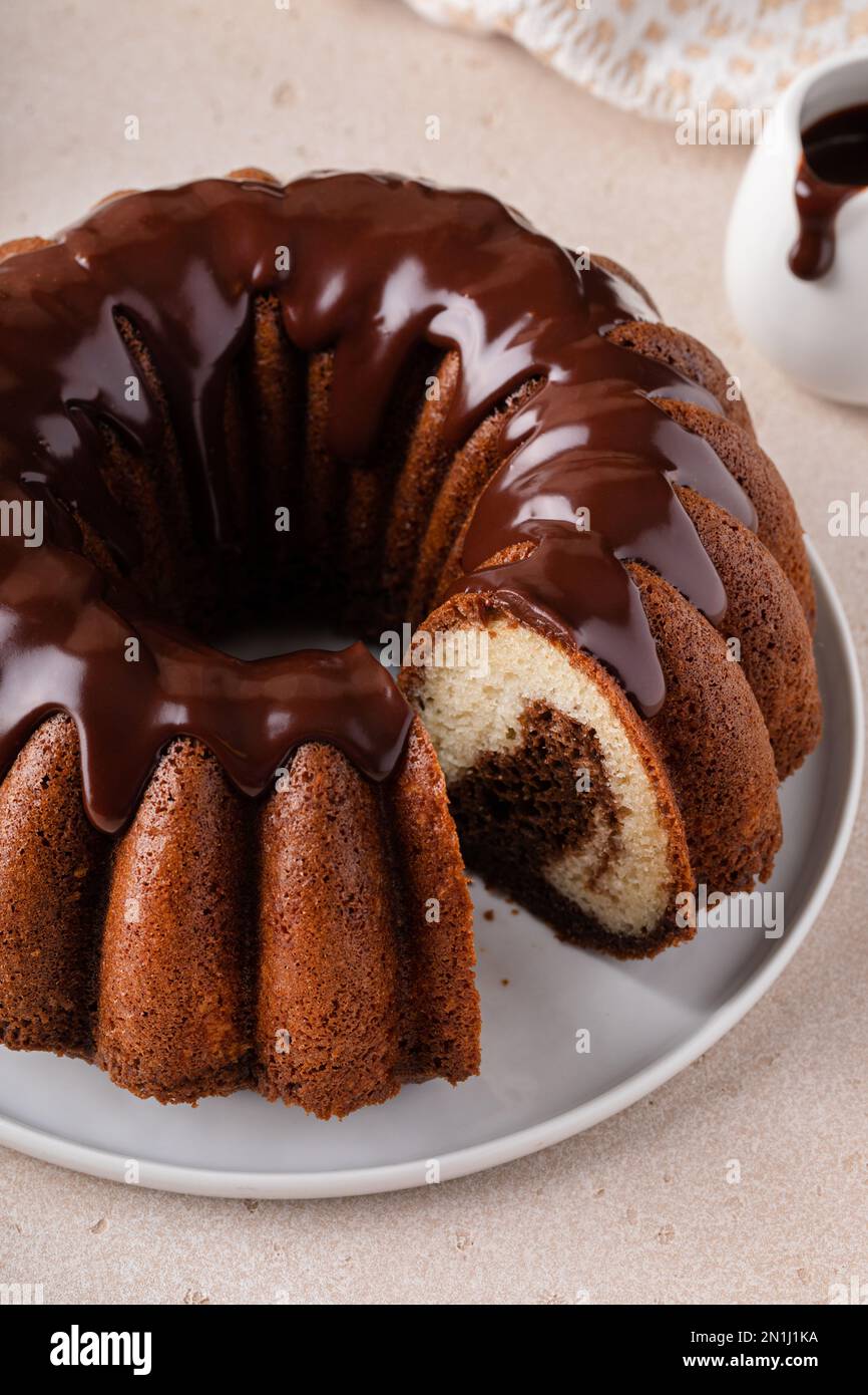 Schokoladenkuchen aus Marmor oder Zebrakuchen mit Schokoladenglasur, die oben mit einer Scheibe aus dem Glas gestreut wird Stockfoto