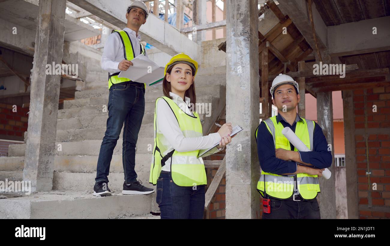 Porträt eines Architekten- und Ingenieurteams in Helmen, die an der Treppe stehen und Entwürfe für Pläne erstellen. Stockfoto