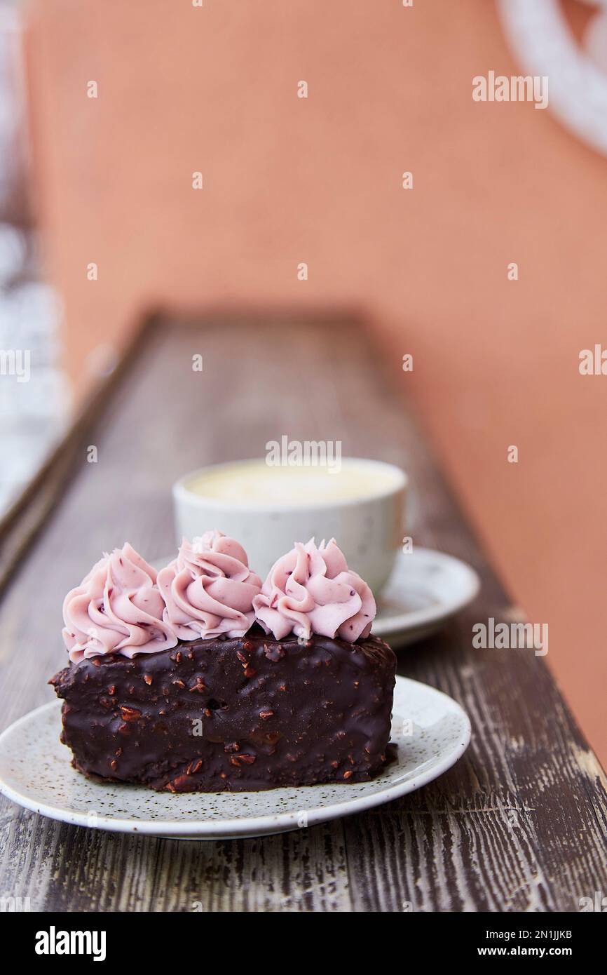 Veganer Brownie-Kuchen mit Tasse Cappuccino. Kaffee mit Dessert, Ästhetik außen, Stockfoto