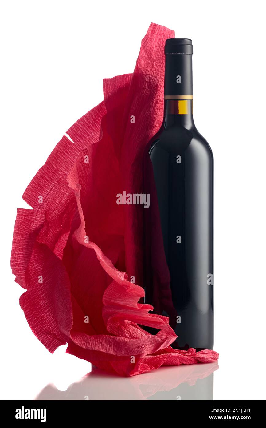 Flasche Rotwein mit zerknittertem roten Krepppapier isoliert auf weißem Hintergrund. Stockfoto