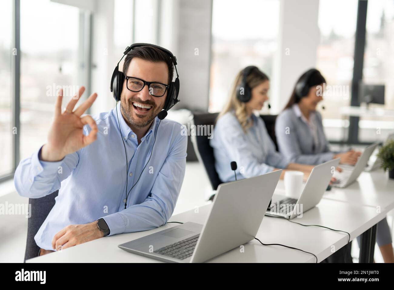 Porträt eines gutaussehenden, bärtigen Geschäftsmanns mit Headset, der im Callcenter-Büro gut singen kann Stockfoto