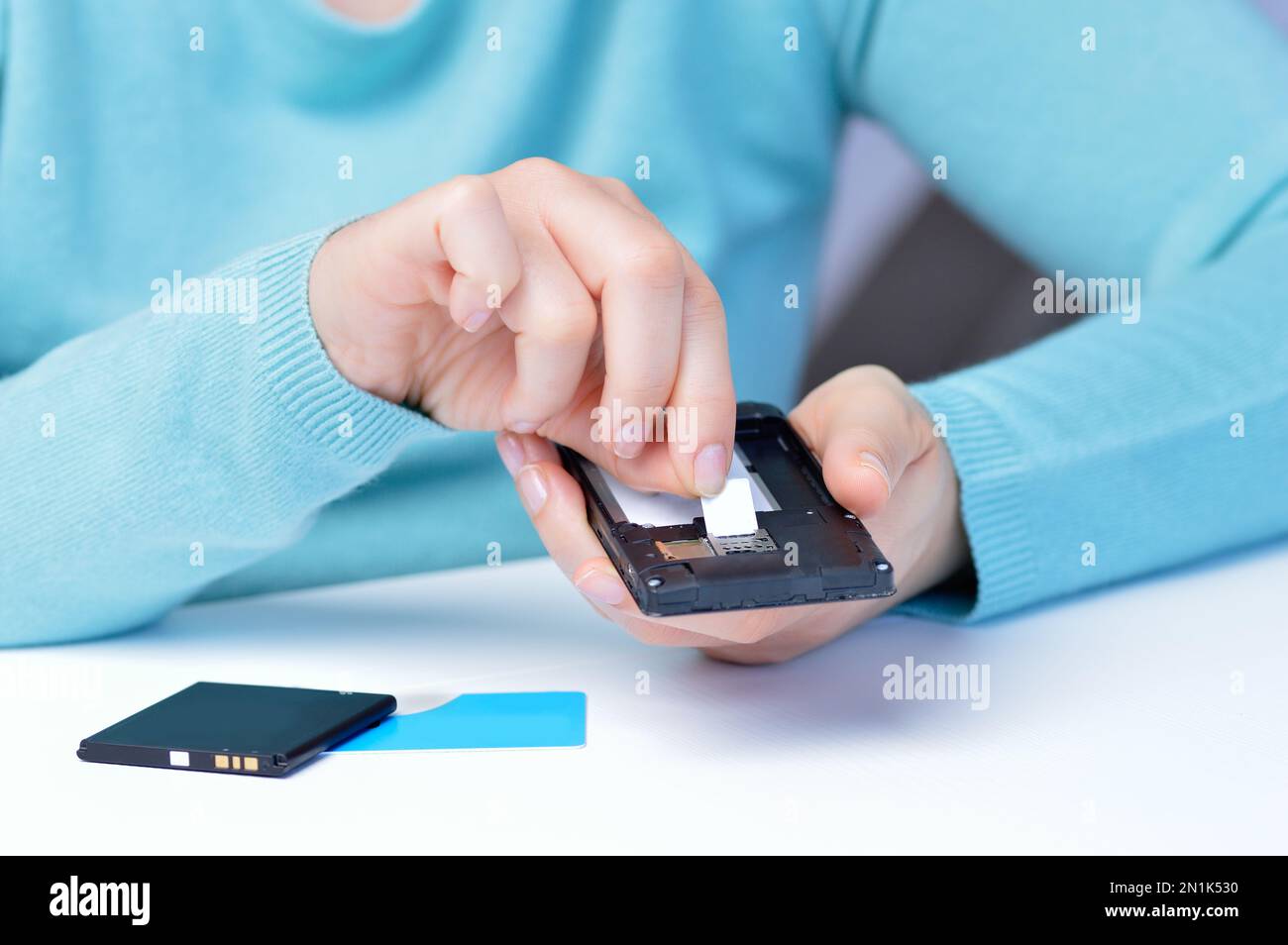 Frauenhände, die die sim-Karte auf das Telefon legen Stockfoto