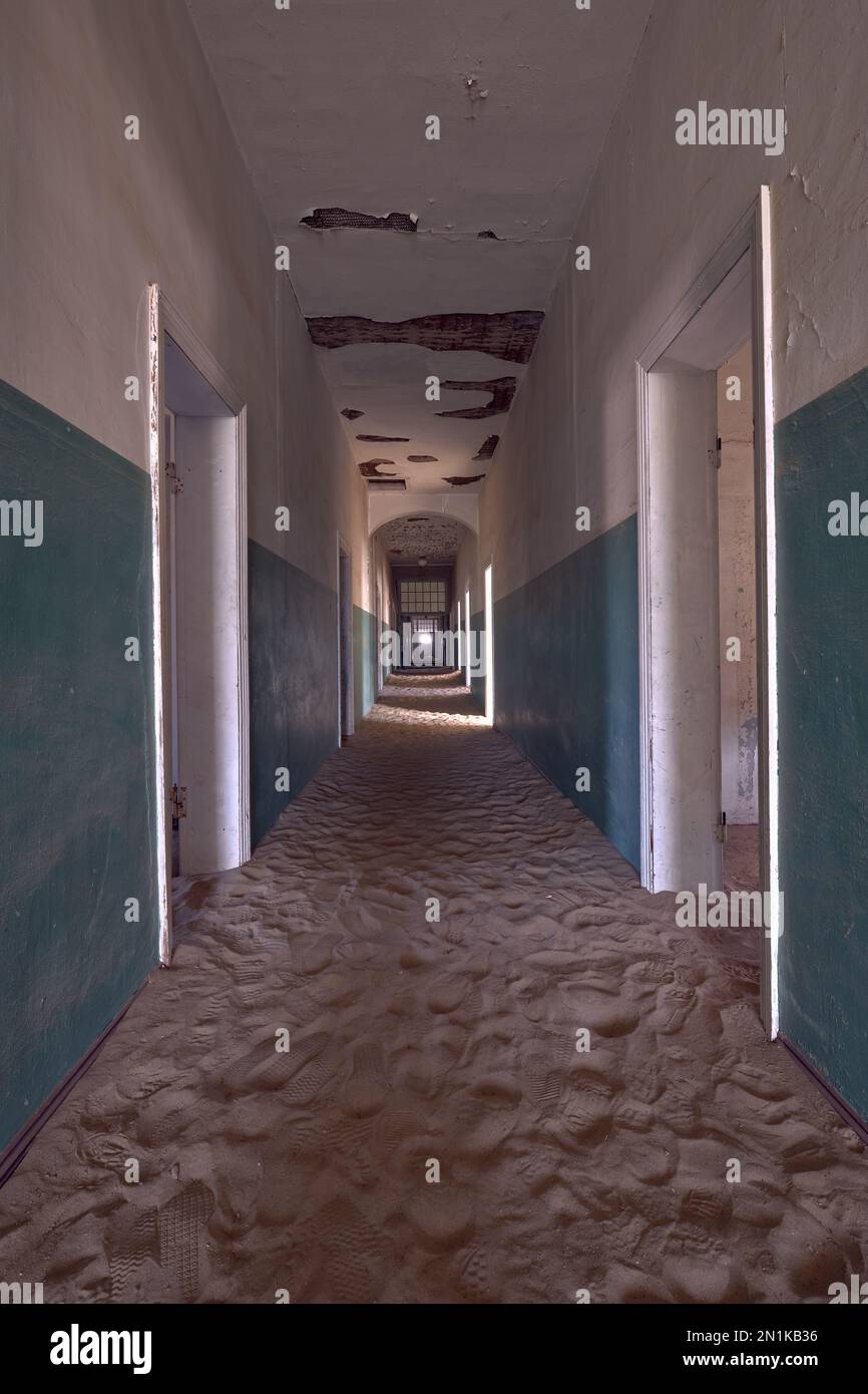 Leerer, mit Sand gefüllter Korridor im Krankenhaus der Geisterstadt Kolmanskop, Namibia. Kreatives, verbessertes Foto. Stockfoto