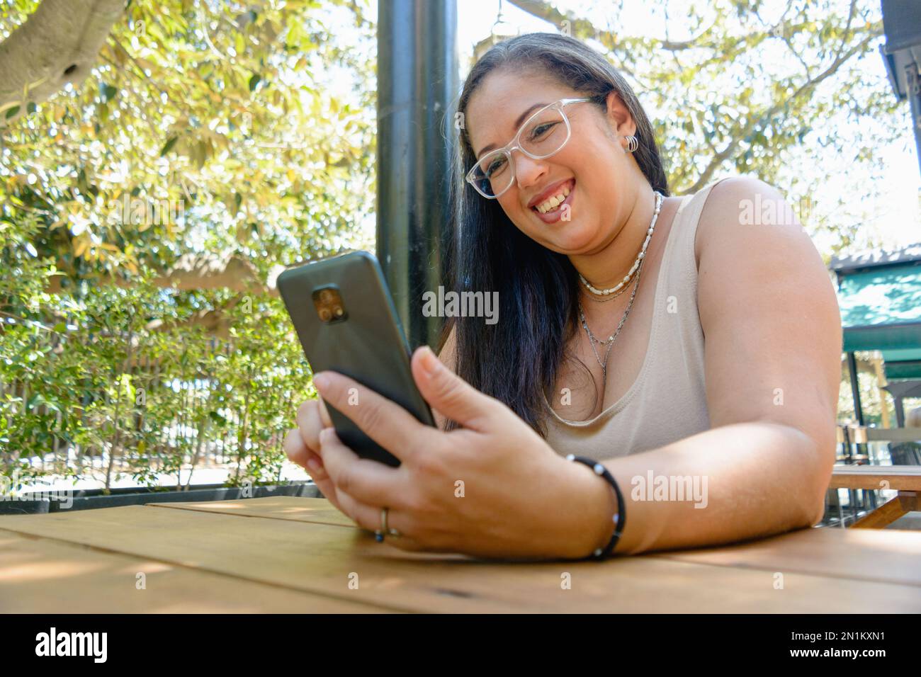 Lateinische Erwachsene Frau venezolanischer ethnischer Herkunft, fröhliches Lächeln, Telefonieren, Unterhaltung beim Surfen in sozialen Netzwerken und Surfen im Internet. Stockfoto
