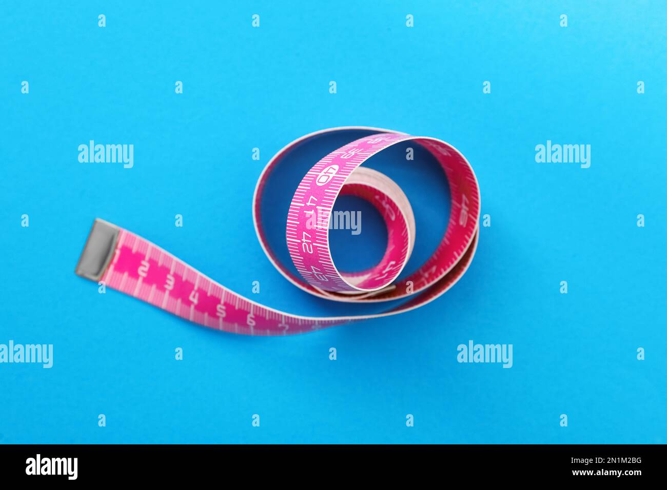 Rosafarbenes Maßband auf hellblauem Hintergrund, Draufsicht Stockfoto