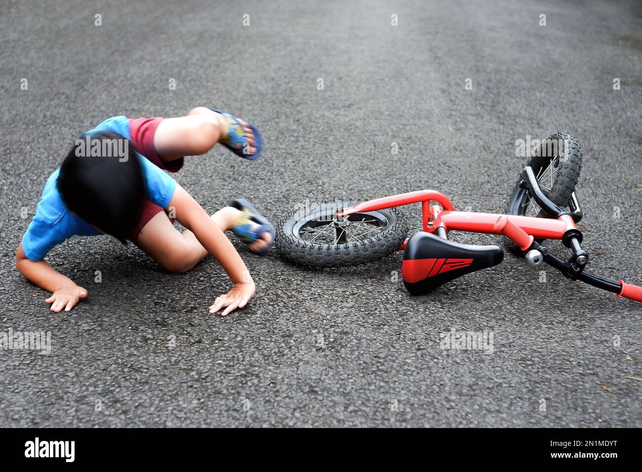 Bewegungsunschärfe ein Kind fällt von einem roten Fahrrad Stockfoto