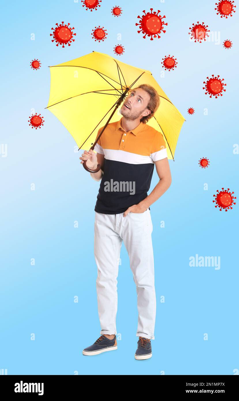 Der Mann schützt sich vor Viren mit gelbem Schirm als Symbol für starke Immunität Stockfoto