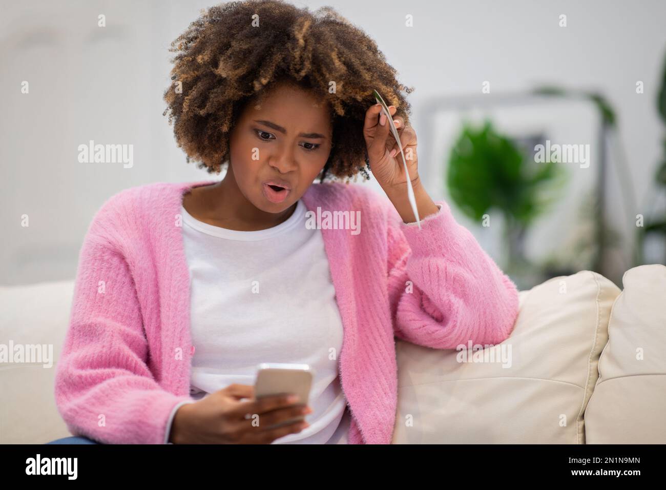 Schockierte schwarze Frau, die auf den Telefonbildschirm schaut, Kopierraum Stockfoto