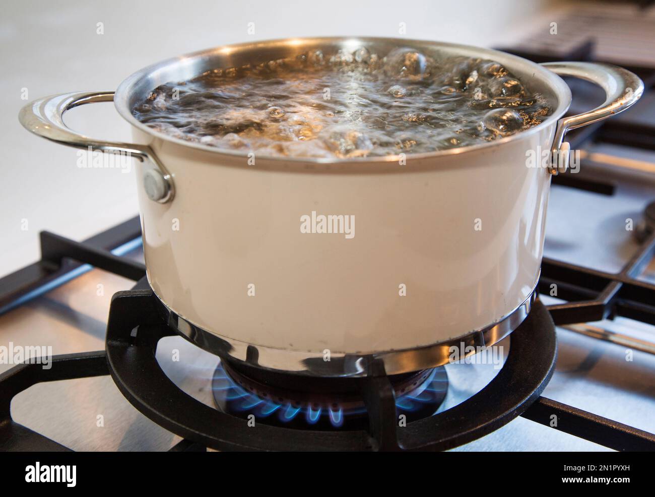 Die Pfanne mit Wasser auf einem Herd wird erhitzt, damit das Wasser kocht. Stockfoto