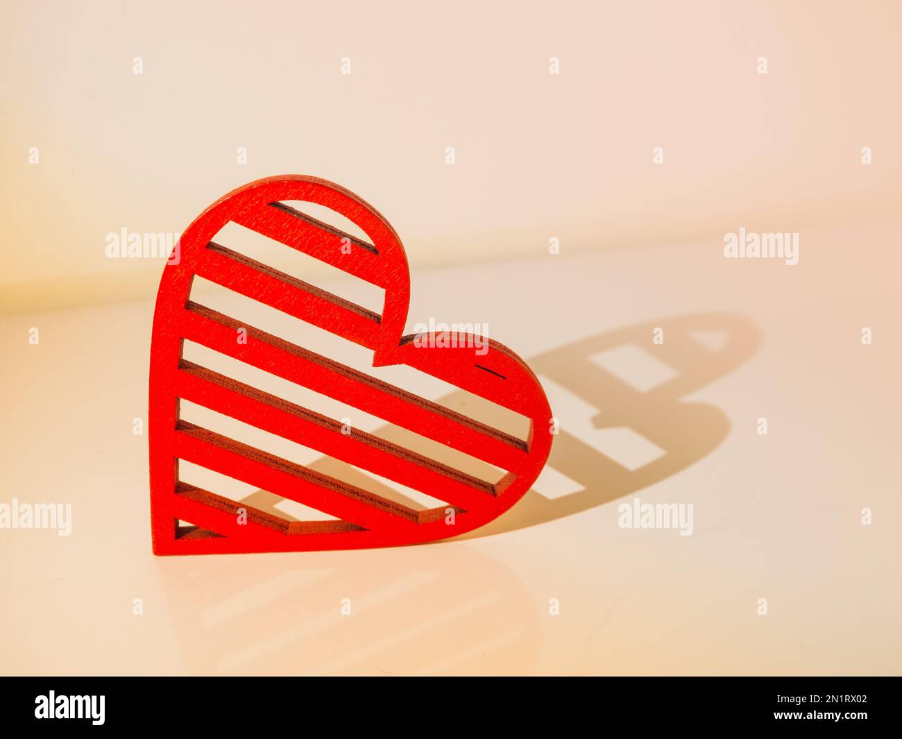 Herzkonzept aus rotem Holz auf hellem Hintergrund mit Herzschatten. Valentinstag. Stockfoto