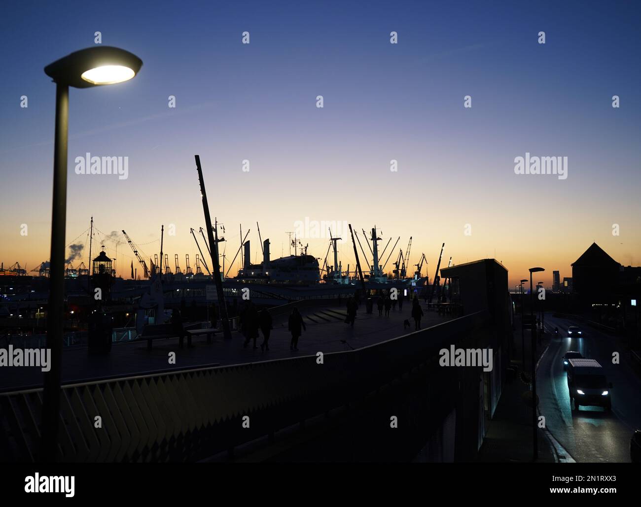 Hamburg, Deutschland. 06. Februar 2023. Passanten gehen entlang der Jan Fedder Promenade im Hafen in der Abendsonne. Kredit: Marcus Brandt/dpa/Alamy Live News Stockfoto