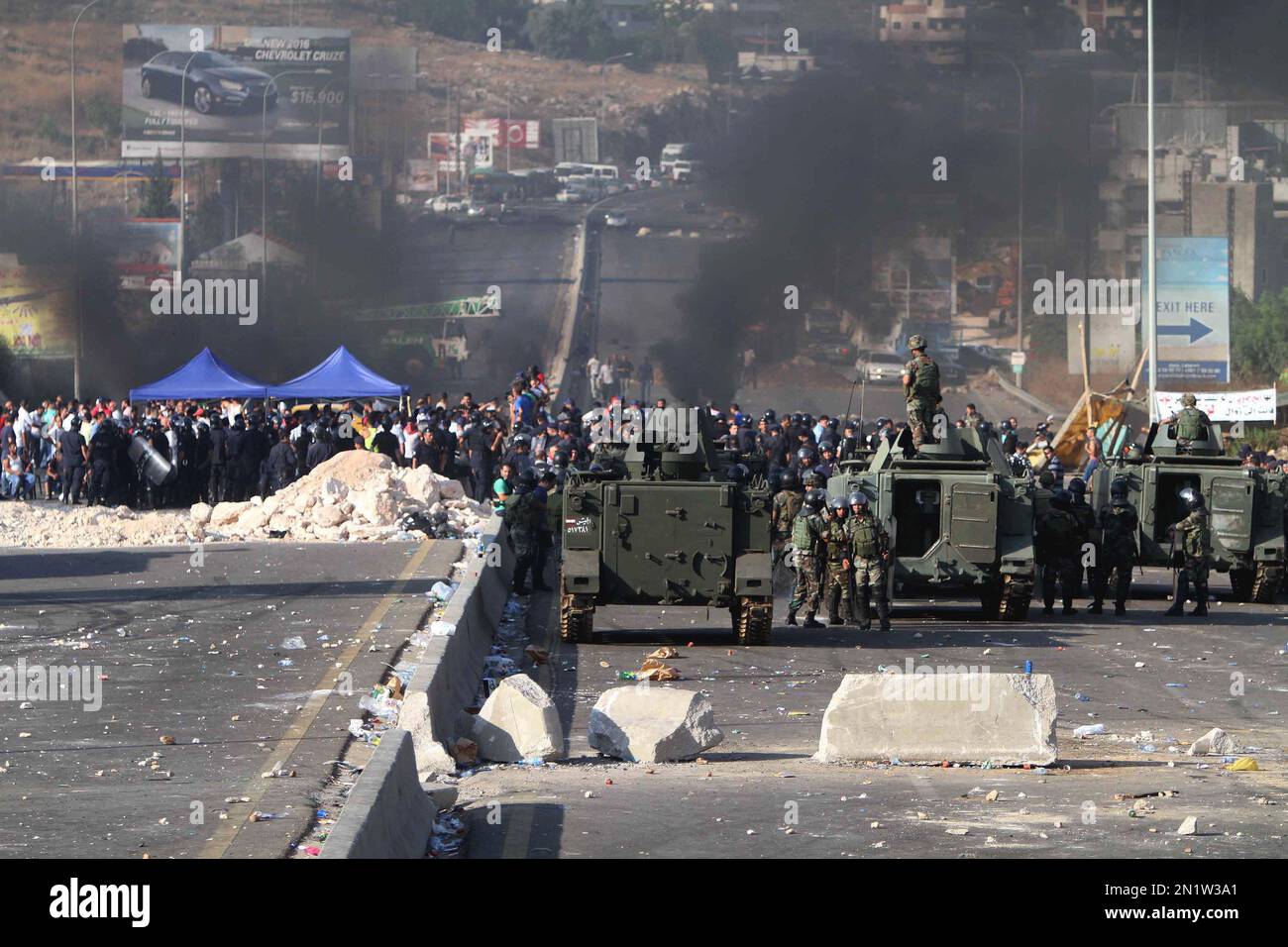 Lebanese army soldiers stand next of their armored personnel carriers as they prepare to reopen a highway linking Beirut to southern Lebanon blocked by angry protesters, in the coastal town of Jiyeh, Lebanon, Monday, July 27, 2015. The closure of the vital highway in the coastal comes amid reports that the government plans to move trash piled on the streets of Beirut to the Kharoub region south of the capital. The main company in charge of collecting trash stopped its work earlier this month amid a dispute over the country's largest trash dump. Mountains of garbage have piled up in Beirut and  Stockfoto