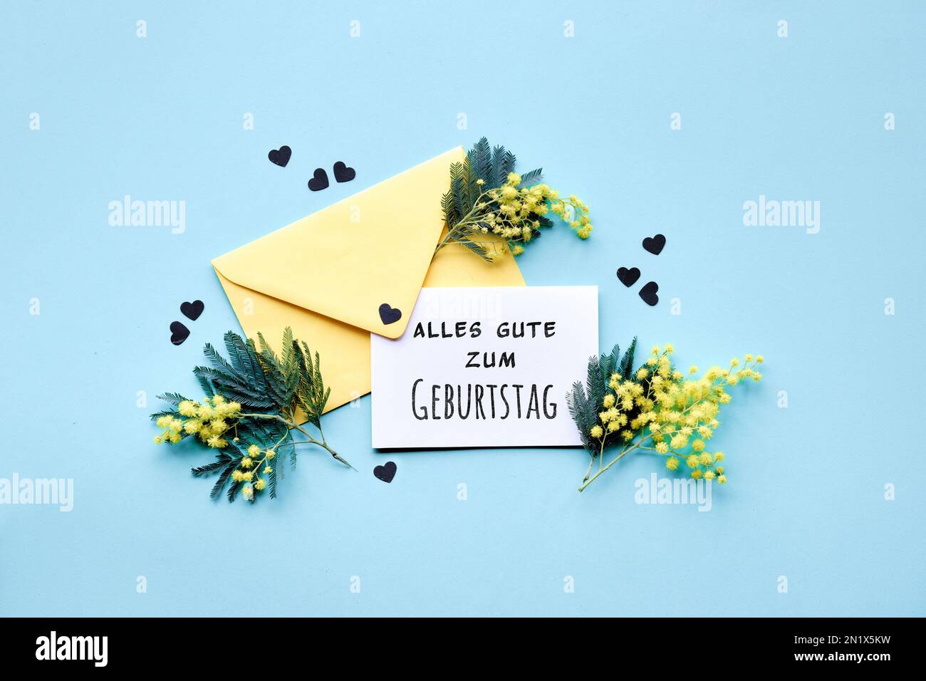 Text Alles Gute zum Geburtstag bedeutet Happy Birthday in deutscher Sprache. Text Special Moments auf Papierkarte mit Mimosablüten in gelbem Umschlag auf m Stockfoto