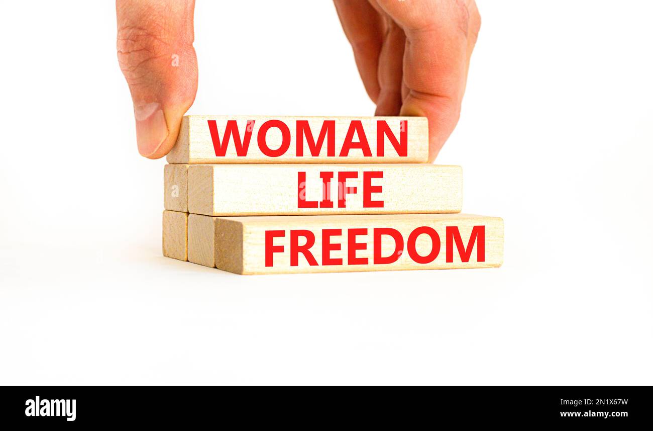 Das Symbol für die Freiheit des Lebens der Frau. Konzeptwörter Woman Life Freedom auf Holzblöcken auf einem wunderschönen weißen Tischhintergrund. Geschäftsmannshand. iss für soziale Medien Stockfoto