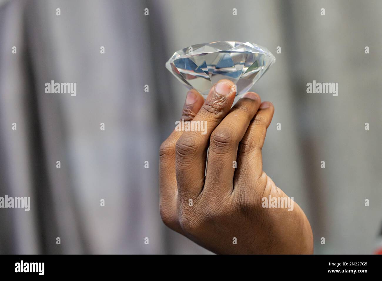 Konzentrieren Sie sich auf den Vordergrund von Fingern, die einen Diamanten halten. Stockfoto