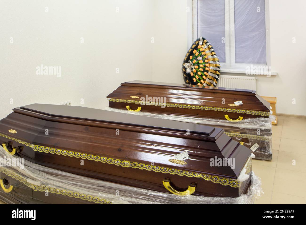 Innenraum des Raumes mit Bestattungszubehör. Geschäft mit Särgen, Beerdigungskränzen und Blumen. Stockfoto