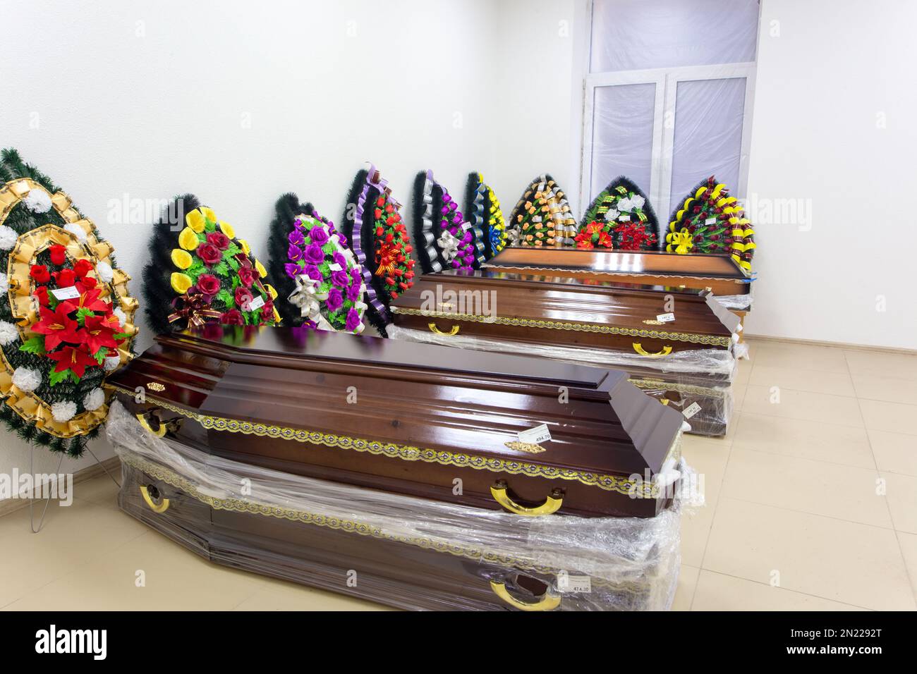 Innenraum des Raumes mit Bestattungszubehör. Geschäft mit Särgen, Beerdigungskränzen und Blumen. Stockfoto