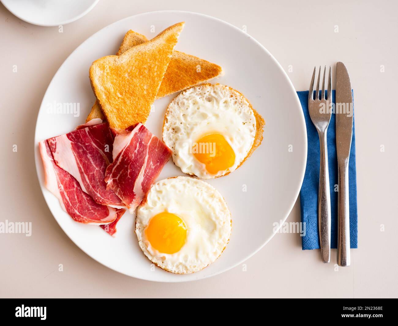 Spiegeleier mit flüssigem Eigelb, geräucherten Schinkenscheiben und Toast Stockfoto