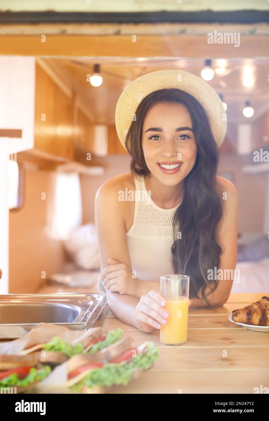 Junge Frau mit einem Glas Saft im Wohnwagen. Campingurlaub Stockfoto