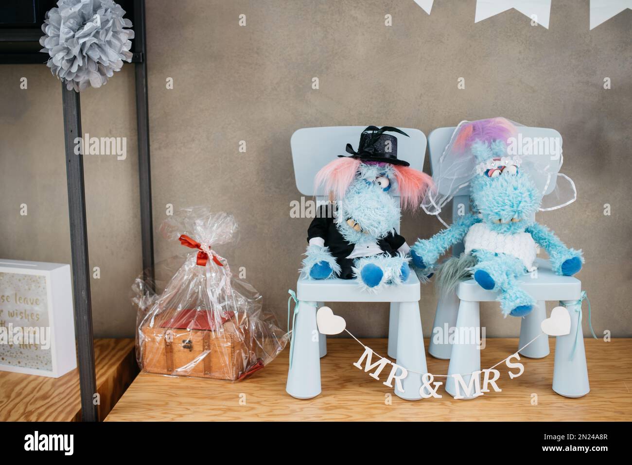 Eine Nahaufnahme von Stoffspielzeugen auf Spielzeugstühlen im Regal, die eine Braut und einen Bräutigam repräsentieren, das Konzept der Hochzeitsdekoration Stockfoto