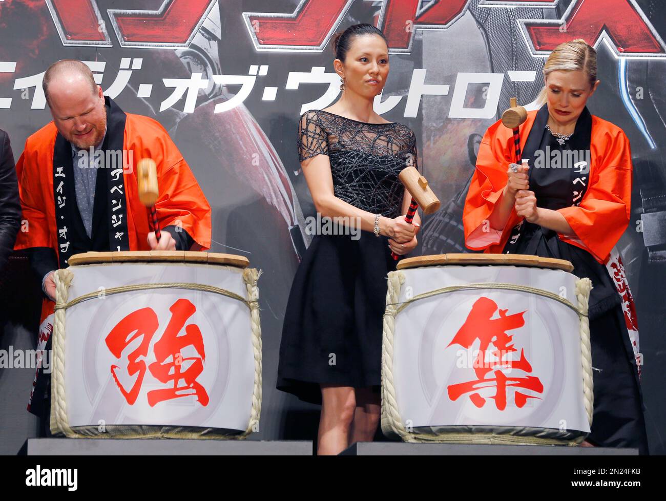 U.S. director Joss Whedon, left, Japanese actress Ryoko Yonekura, center, and U.S. actress Elizabeth Olsen pound the casks of Japanese sake to celebrate the Japan premiere of Avengers: Age of Ultron in Tokyo,Tuesday, June 23, 2015. Chinese characters on the casks read a part of: "Mightiest Team." (AP Photo/Shizuo Kambayashi) Stockfoto