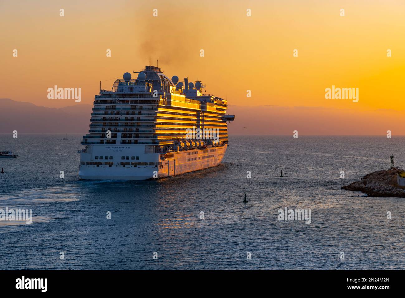 Ein großes Kreuzfahrtschiff verlässt den Hafen von Puerto Vallarta, Mexiko, bei Sonnenuntergang. Stockfoto