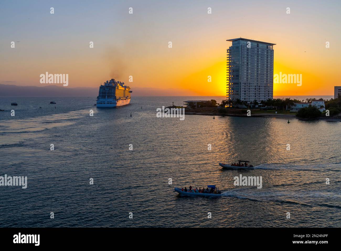 Ein großes Kreuzfahrtschiff verlässt den Hafen von Puerto Vallarta, Mexiko, bei Sonnenuntergang. Stockfoto