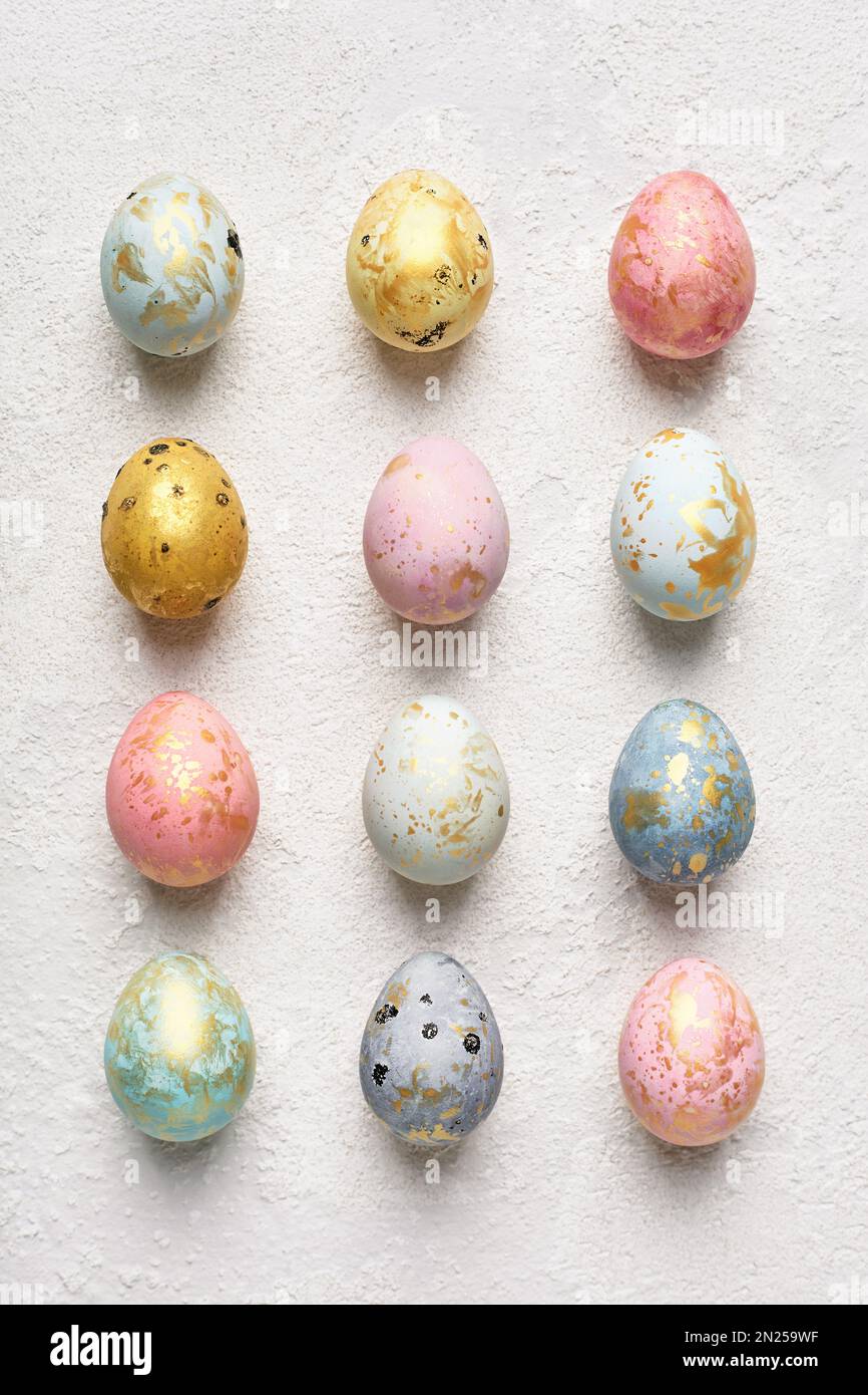 Schicke Ostereier in Pastelltönen mit Gold auf weißem Hintergrund. Flaches geometrisches Muster. Frohe Osterkarte. Stockfoto