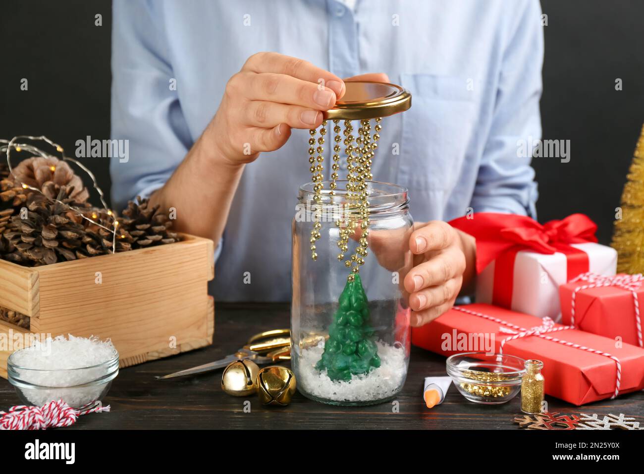 Frau, die Schneekugel am schwarzen Holztisch macht, Nahaufnahme Stockfoto