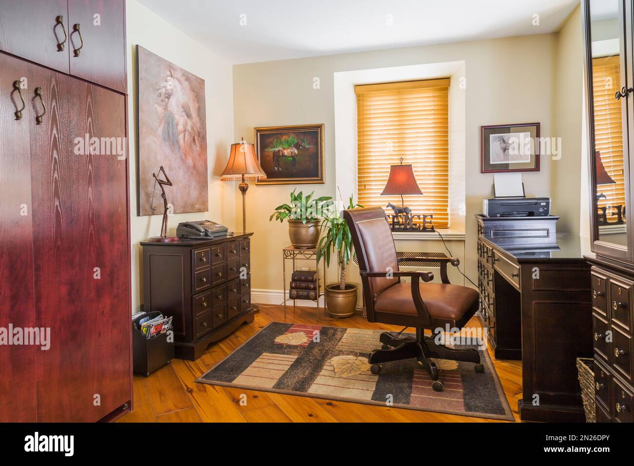 Home Office mit herrschaftlich braunem Ledersessel und Schreibtisch in einer Ecke des Wohnzimmers im alten, renovierten Haus im Canadiana Cottage Stil aus dem Jahre 1840. Stockfoto