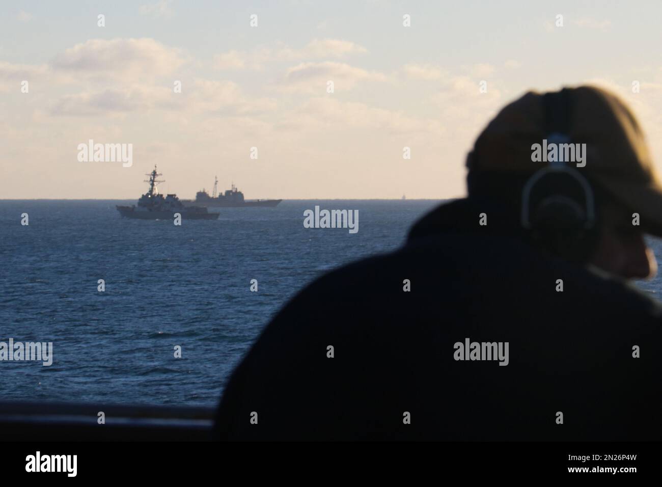 Der Seemann Rafael Mendez steht an Bord der USS Carter Hall (LSD 50) und beobachtet, wie der Zerstörer USS Oscar Austin (DDG 79) und der Kreuzfahrer USS Philippine Sea (CG 58) neben Trümmern aus einem chinesischen Ballon mit Höhenüberwachung umhertransportieren. Auf Anweisung des Präsidenten der Vereinigten Staaten und mit voller Unterstützung der kanadischen Regierung, US-Kampfflugzeuge unter U.S. Die Northern Command Authority hat am 4. Februar 2023 einen Überwachungsballon in großer Höhe im US-Luftraum und über US-Hoheitsgewässern zum Absturz gebracht. Carter Hall ist der Stockfoto