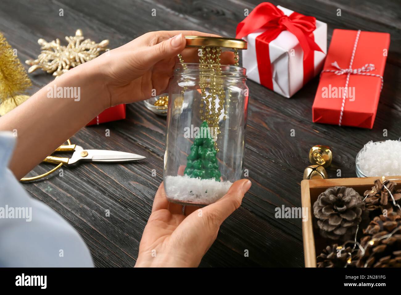 Frau, die Schneekugel am schwarzen Holztisch macht, Nahaufnahme Stockfoto