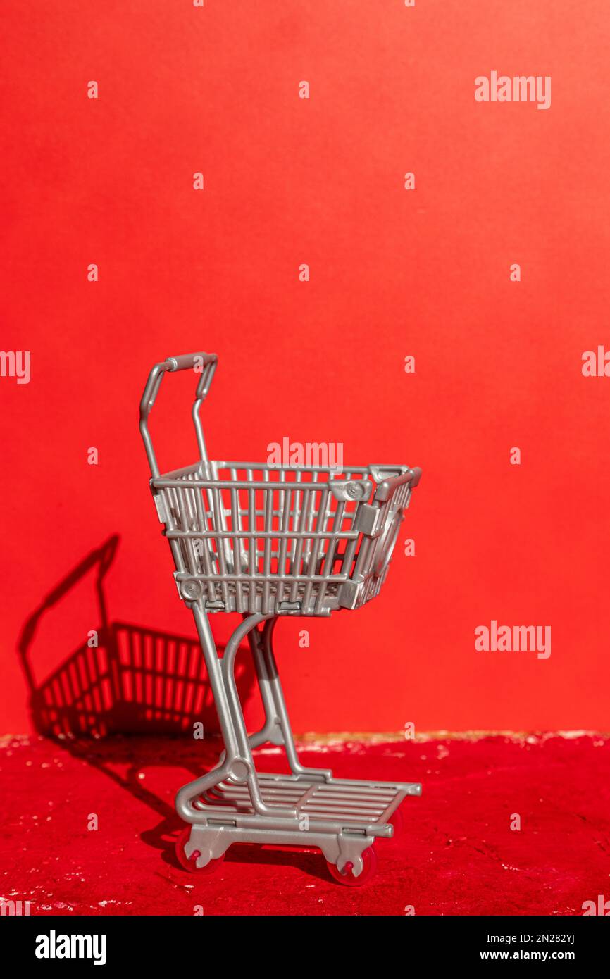 Supermarkt-Wagen auf rotem Hintergrund. Konzeptionell. Stockfoto