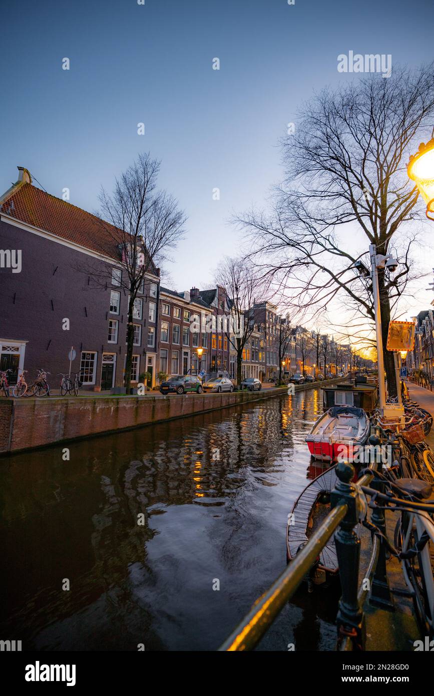 Blick Auf Den Amsterdamer Kanal. Farbenfrohe und historische Gebäude in Amsterdam, Niederlande. Amsterdam in der Abenddämmerung im Februar. Stockfoto