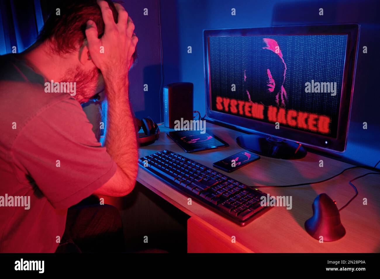 Gestresster Mann, der seinen Kopf vor dem Desktop-Computer hält und die Warnung „System-Hacker“ anzeigt, während ein mysteriöser Kapuzenmann mit gehacktem Pho auftaucht Stockfoto