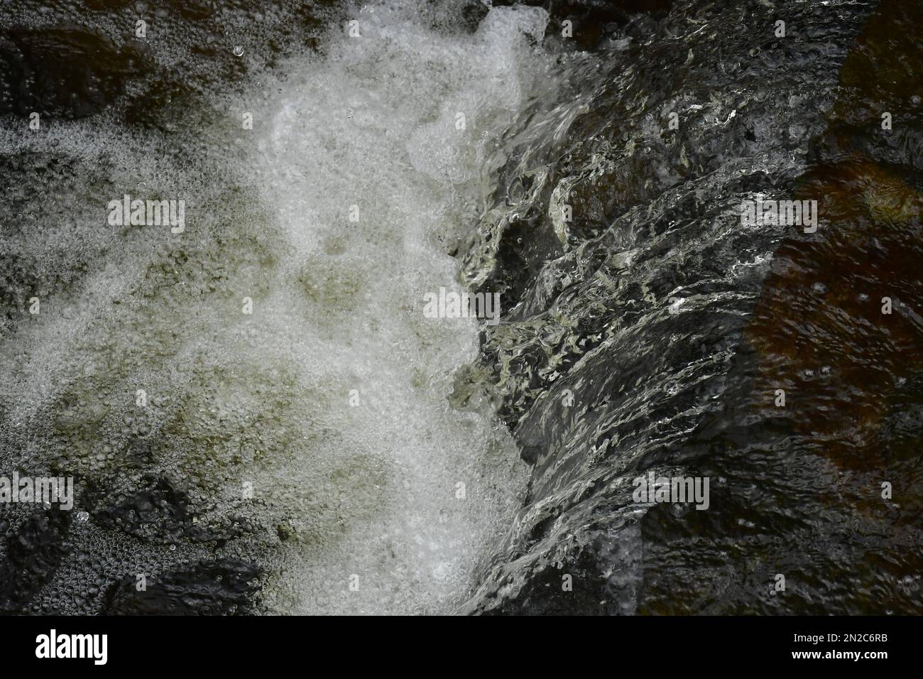 Wasser stürzt in einen kleinen Wasserfall in einem Garten. Stockfoto