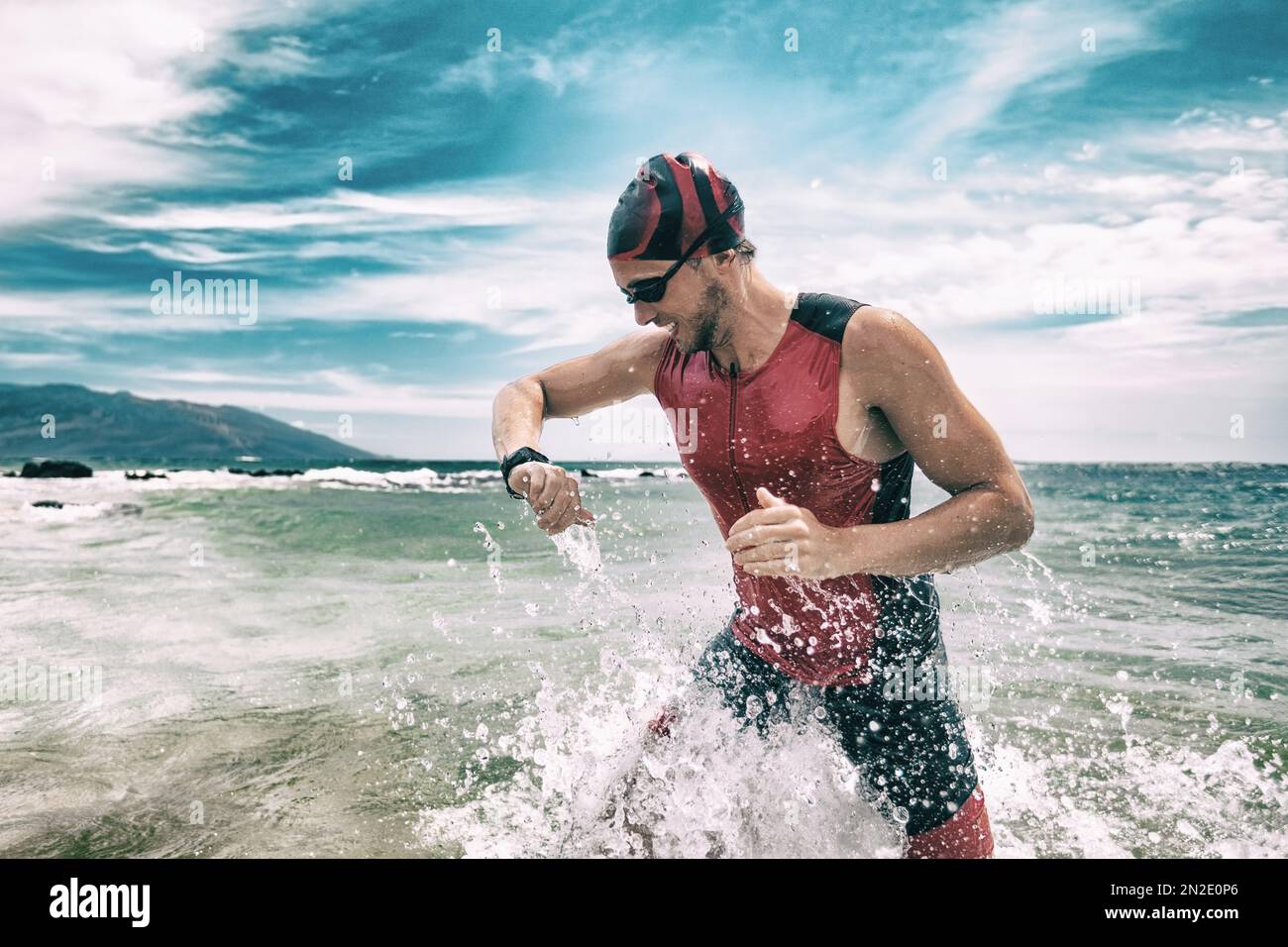 Triathleschwimmer, der während des Triathlons mit Smartwatch auf die Sport Watch App schaut. Schwimmender Mann, der aus dem Meer rennt, schwimmt und die Herzfrequenz auf Smart überprüft Stockfoto