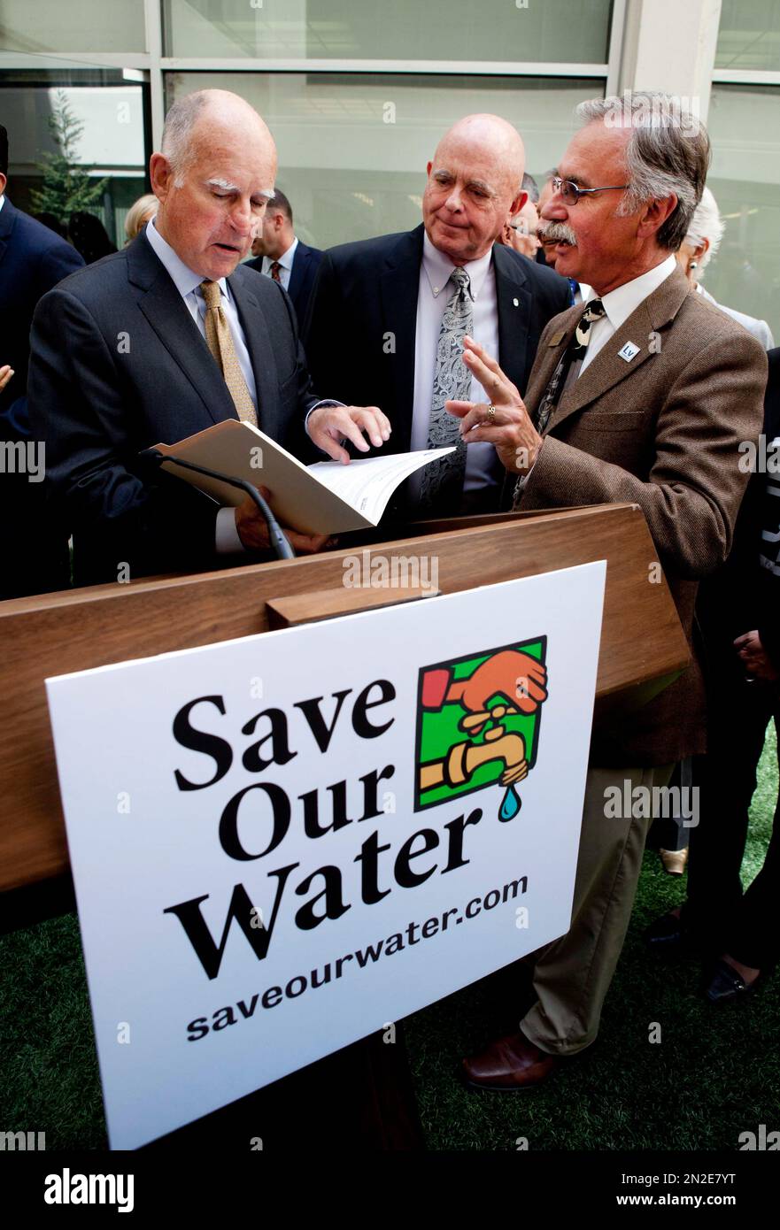 Gov. Jerry Brown, left, talks with Livermore Mayor John Marchand, right, and Rancho Cucamonga Mayor L. Dennis Michael, center, during a news conference after meeting with several California mayors to discuss water conservation at the Capitol in Sacramento, Calif., on Tuesday, April 28, 2015. Gov. Brown called for $10.000 fines for residents and businesses that waste the most water as California cities try to meet mandatory conservation targets during the drought. (AP Photo/Steve Yeater) Stockfoto