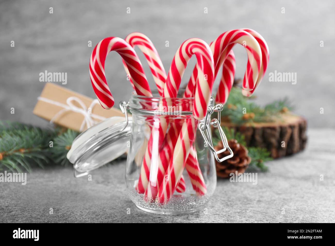 Weihnachtliche Zuckerstangen im Glasglas auf einem grauen Tisch Stockfoto