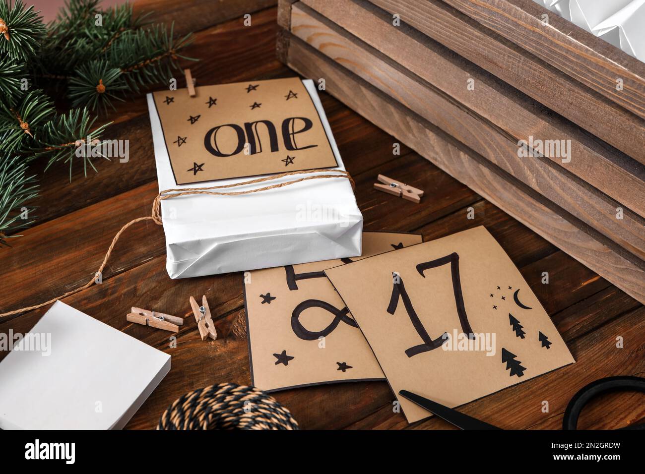 Komposition mit Geschenktasche und Notizen auf Holztisch, Nahaufnahme. Adventskalender wird erstellt Stockfoto