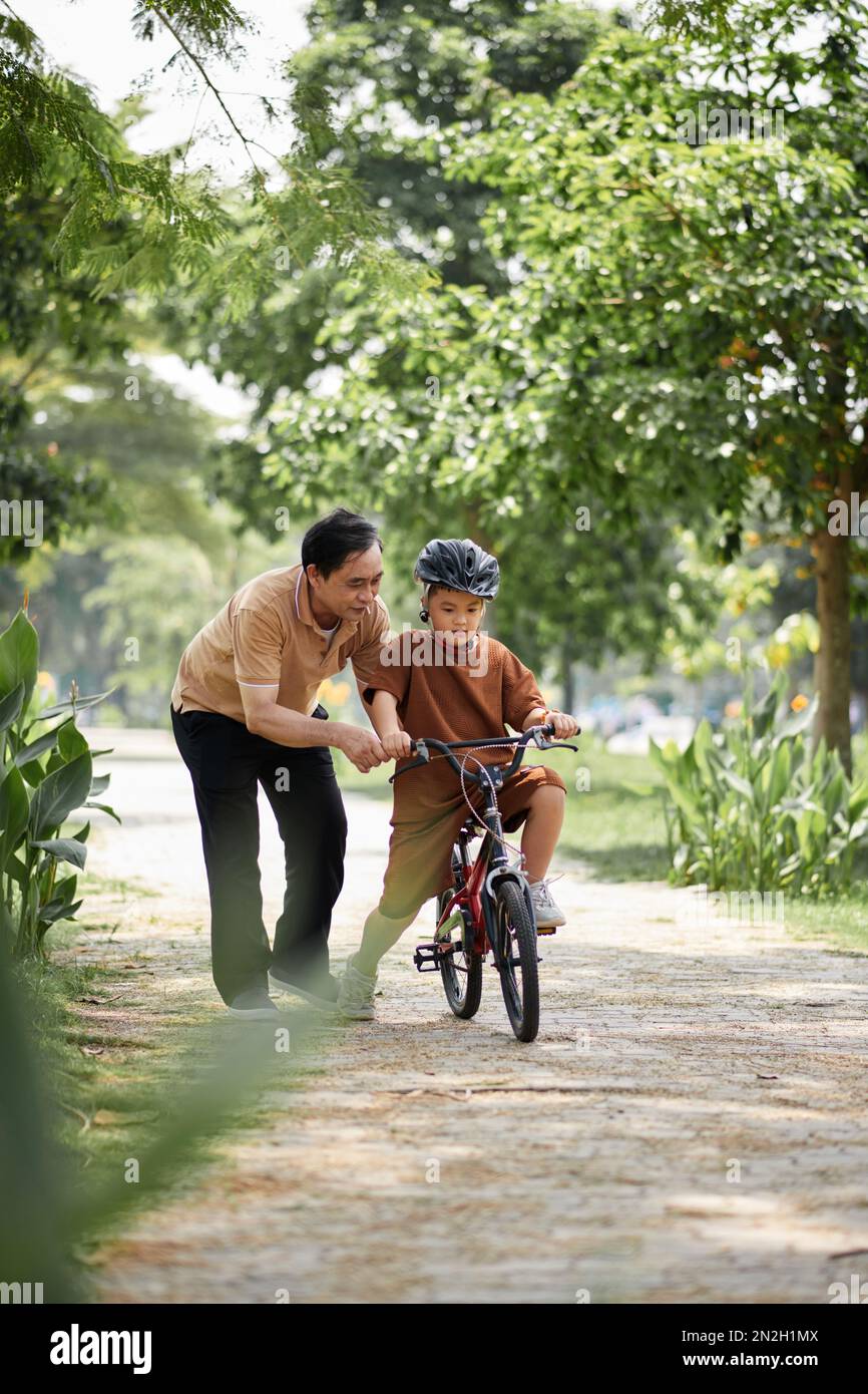 Großvater hilft dem jungen Enkel, Fahrrad zu fahren Stockfoto