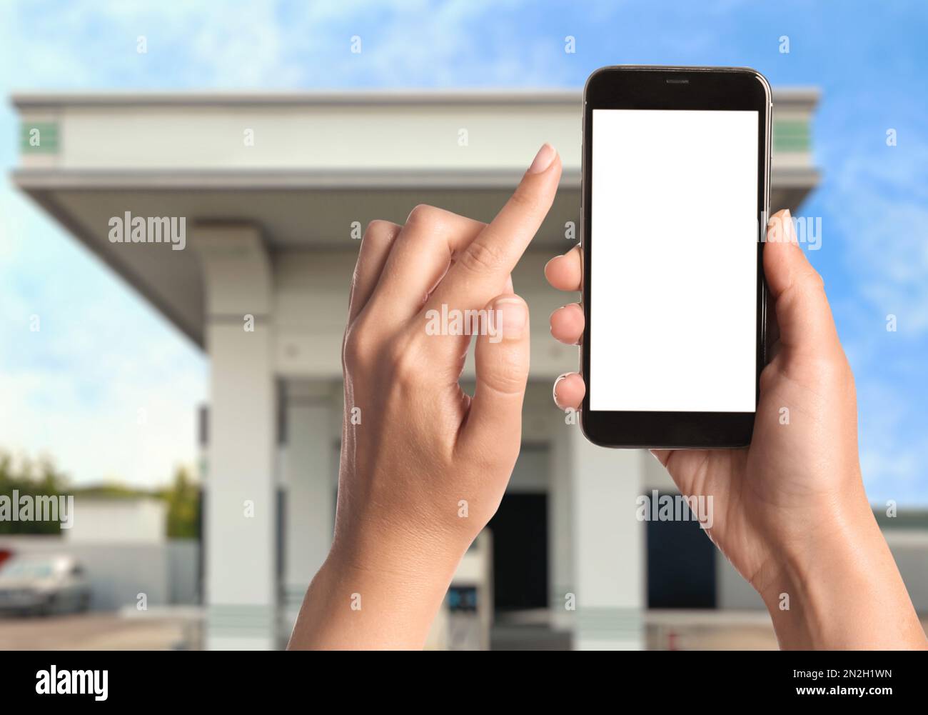Frau, die für das Betanken per Smartphone an der Tankstelle bezahlt, Nahaufnahme. Gerät mit leerem Bildschirm Stockfoto