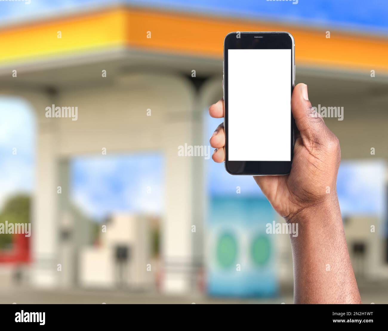 Ein afroamerikanischer Mann, der per Smartphone für das Betanken an der  Tankstelle bezahlt, Nahaufnahme. Gerät mit leerem Bildschirm  Stockfotografie - Alamy