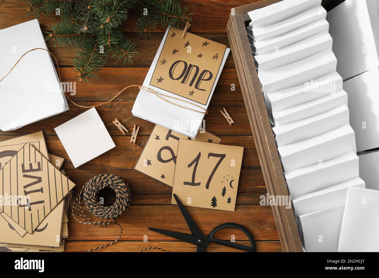 Flach liegend mit Geschenktaschen und Tannenbaum auf Holztisch. Adventskalender wird erstellt Stockfoto